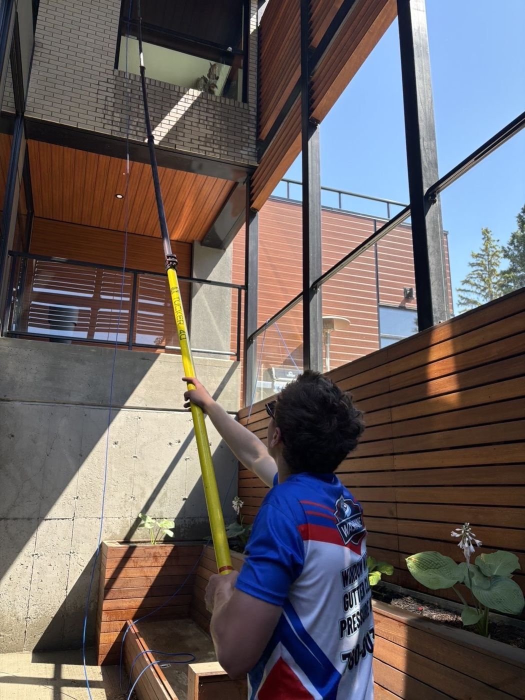 Water-fed pole reaching a modern home's upper windows