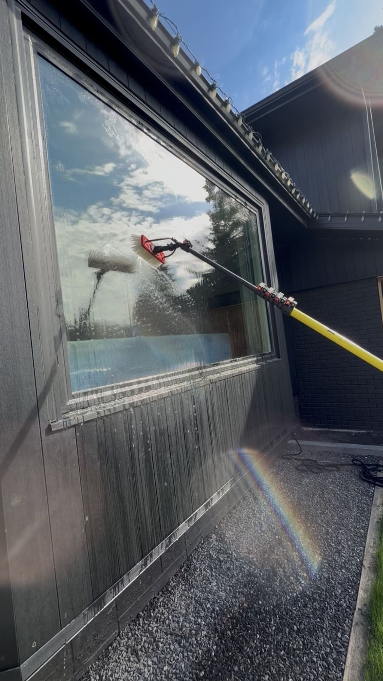 Wash & Shine Co. technician scrubbing a second-story window with a brush pole
